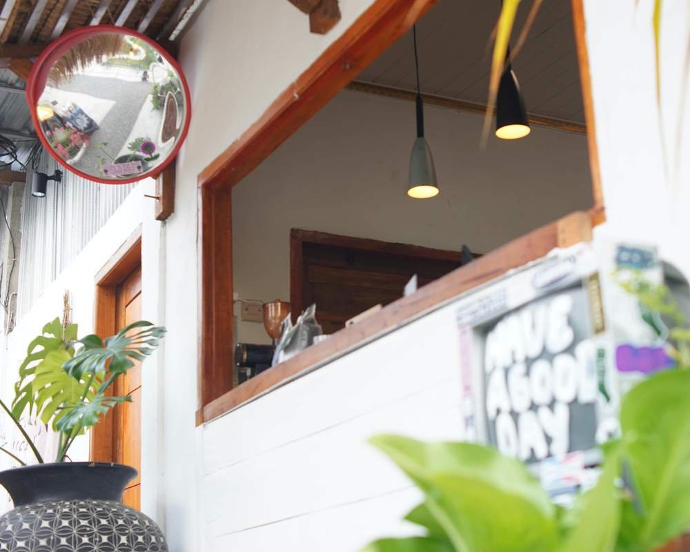 The HAYY DAPOER bar with a round red mirror, pendant lamps and a monstera
