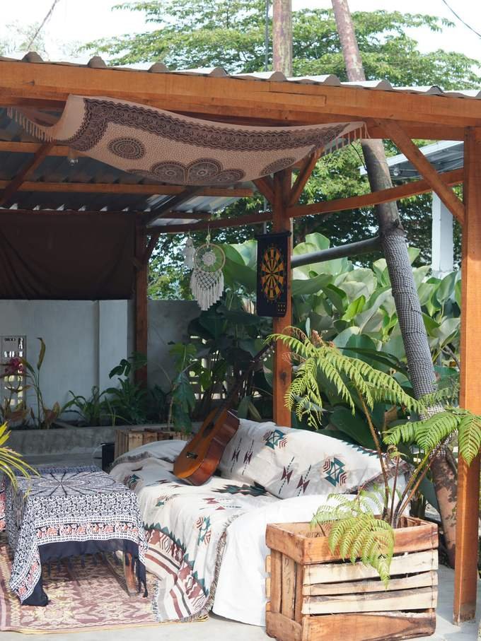 A floor-seating corner with a patterned mattress, a guitar and ferns